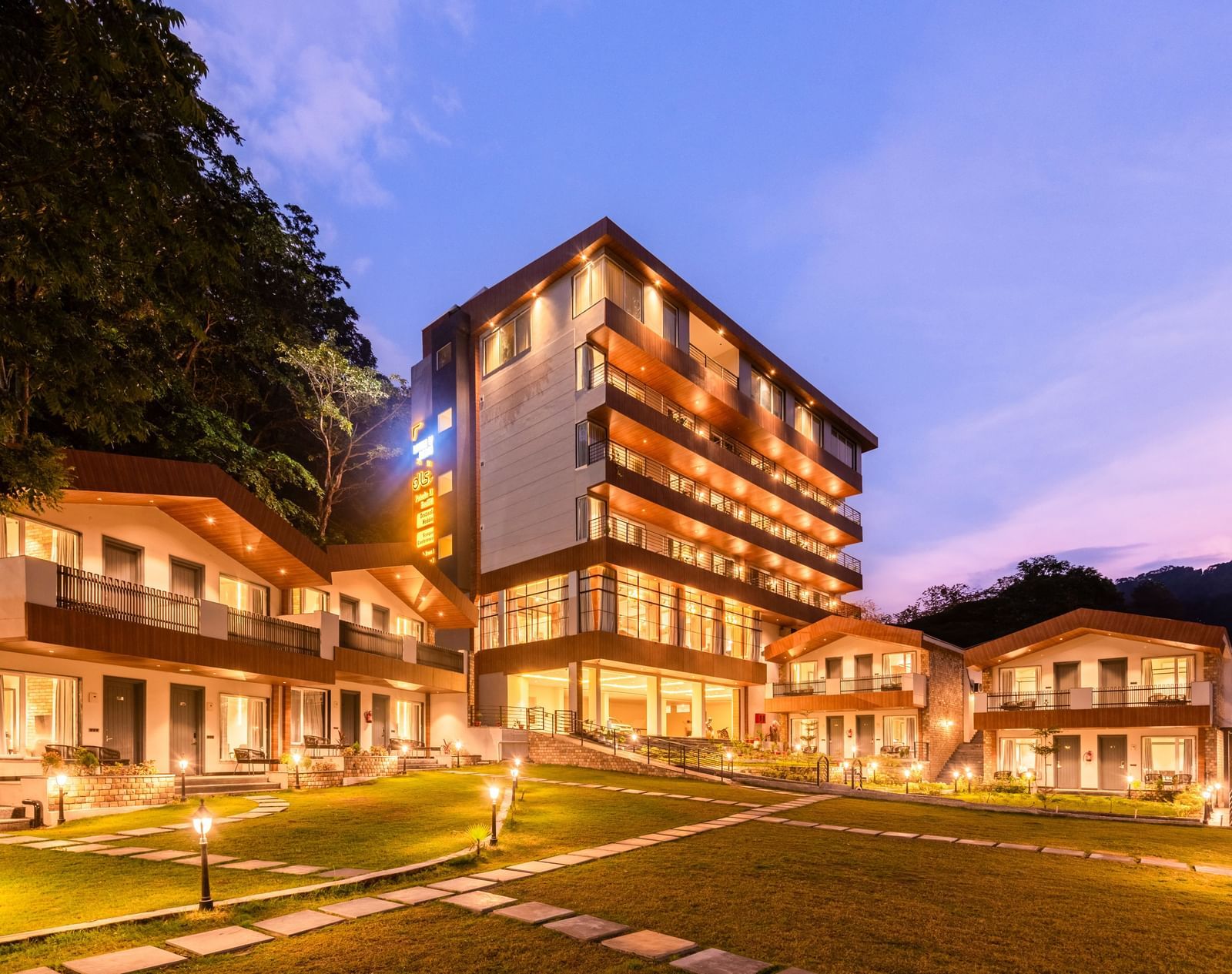 Exterior facade view of DLS Divine River Resort and Spa with warm lighting and garden area taken in the evening 